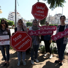 A number of protesters hold placards; one reads "stop violence against women."