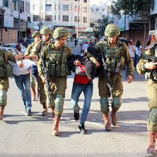 Armed soldiers detain two handcuffed men 