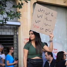 A woman holds up a sign with Arabic writing on it.