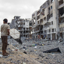 Boy holds kite in front of bombed-out multi-story buildings