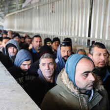 Men queue in a concrete walkway