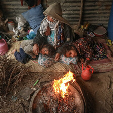 A woman and two children sitting near fire