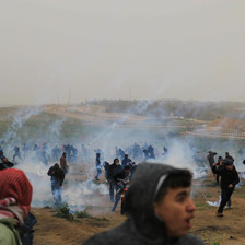 People in a field run amid streaks of smoke 