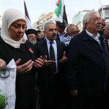 A crowd of people turn their palms upward in prayer