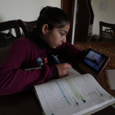 Girl looks at phone and writes in book 