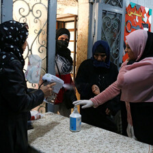 A woman sprays another woman's hands as two women look on