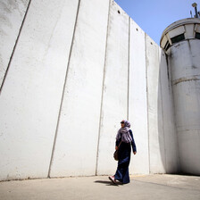 Woman walks past wall and tower
