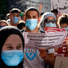 People wearing protective masks hold signs at protest 