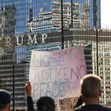 People hold protest signs in front of Trump building