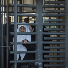 A woman pushes at the metal bars of a caged turnstile