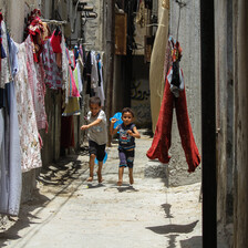 Two children play in a narrow alley where washing has been hung