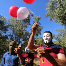 Man with mask holds a number of balloons 