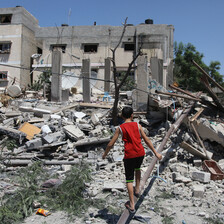 Boy stands in the remains of a badly damaged building 