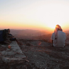 Man sits on rocky outcrop with back to camera 