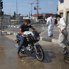 Man wearing white hoses down a motorcycle 