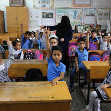 Children raise their hands in a classroom