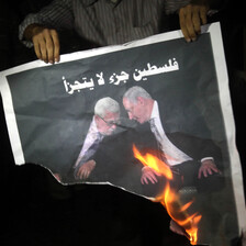 Man holds burning poster of two men 