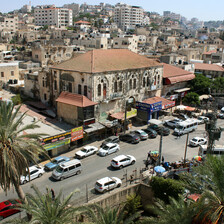 A view over a city, with buildings, traffic and just two trees