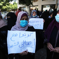 Women in face masks carry posters during a protest