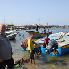 Three men stand near fishing vessels