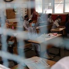 Schoolchildren are seen in their classroom through a wire mesh