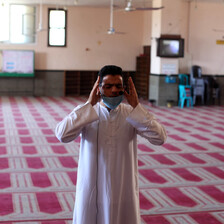 A man raises his hands to his head in prayer