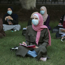 Women wearing masks sit outdoors 