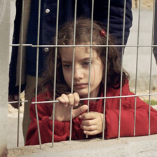 A girl stands behind a metal grill