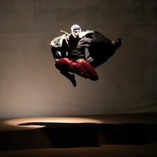 A man in traditional Palestinian black and white headgear flies through the air