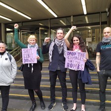 Five people raising fists and holding two signs