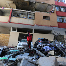 Man stands beside a badly damaged building 