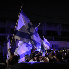 Protesters wave Israeli flags during the night