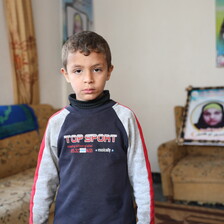 Boy stands in front of framed photograph 