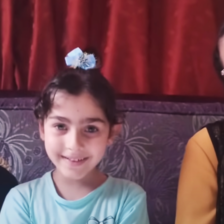 A boy and two girls are seated next to each other on a couch 