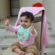A young child sits on a chair and smiles 