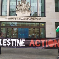 Two protesters hold a "Palestine Action" banner outside a court