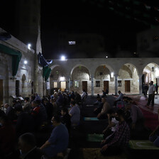 Men pray in the dark in an outdoor mosque courtyard