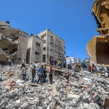 People walk over rubble of destroyed buildings 