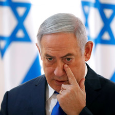 Benjamin Netanyahu touches a finger to his face