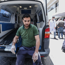 A man rests by the open back of an ambulance