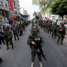 A parade of masked men, carrying guns 