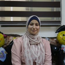 A woman poses with two balloon graduates
