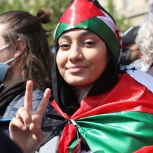 A woman draped in the Palestinian flags gives the victory sign