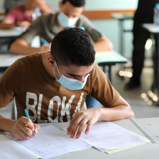 Boy wearing mask writes on paper 