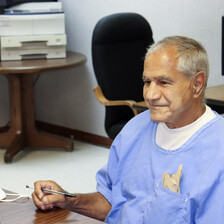 Smiling man sits in front of computer screen