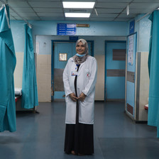 Woman wearing white coat stands in a hospital ward 