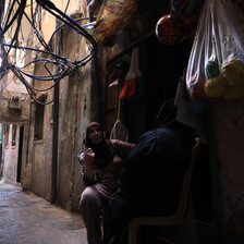 Two women sit outside a shop 