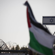 A Palestinian flag flutters in front of an Israeli flag