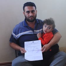 Man holds piece of paper and child 