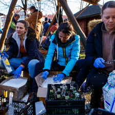 People in a park work over crates full over bottles